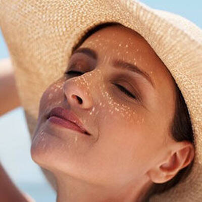 A woman applying Lancome sunscreen cream to her face