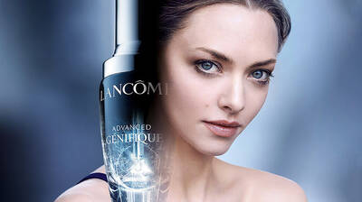 Lancome Advanced Genifique serum bottle next to a close-up of a woman's face with clear, radiant skin, highlighting the product's effectiveness