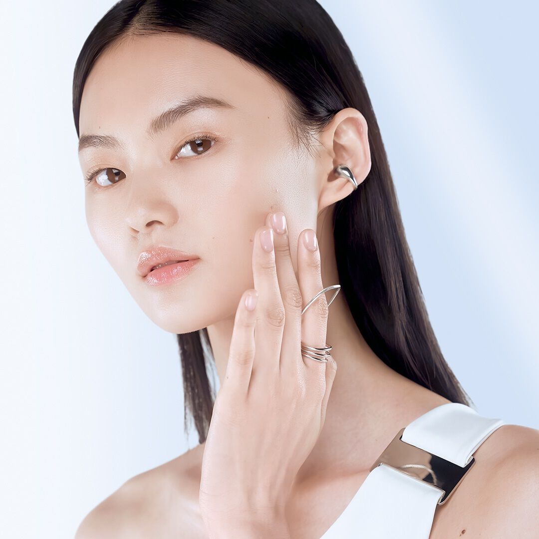 Model gently applying Lancome Clarifique Essence - Demonstrating the benefits of refined skin texture and radiant glow.