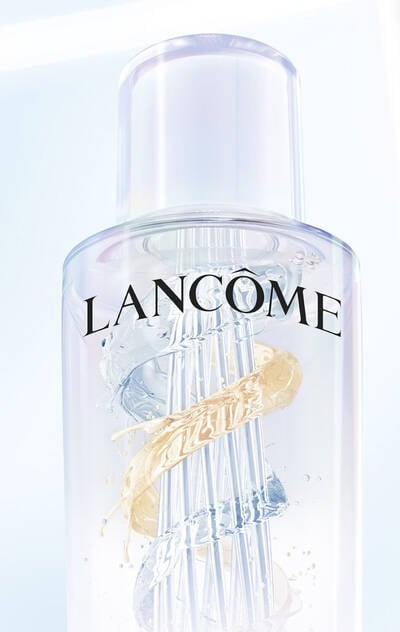 Close-up of the Lancome Clarifique Double Treatment Essence bottle showcasing its dual-phase formula with gold and clear swirls for brightening and hydration.