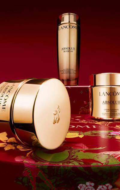 Lancome Absolue Soft Cream and Rose 80 Serum on a red floral surface.