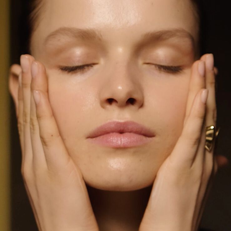 Model applying Lancome Absolue L’Extrait The Elixir Lotion - Gentle hydrating mist for radiant and smooth skin.