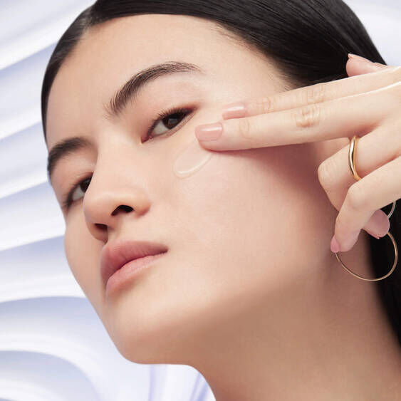 Model applying Lancome Renergie H.C.F. Triple Anti-Ageing Serum to her cheek, demonstrating the lightweight texture of the serum