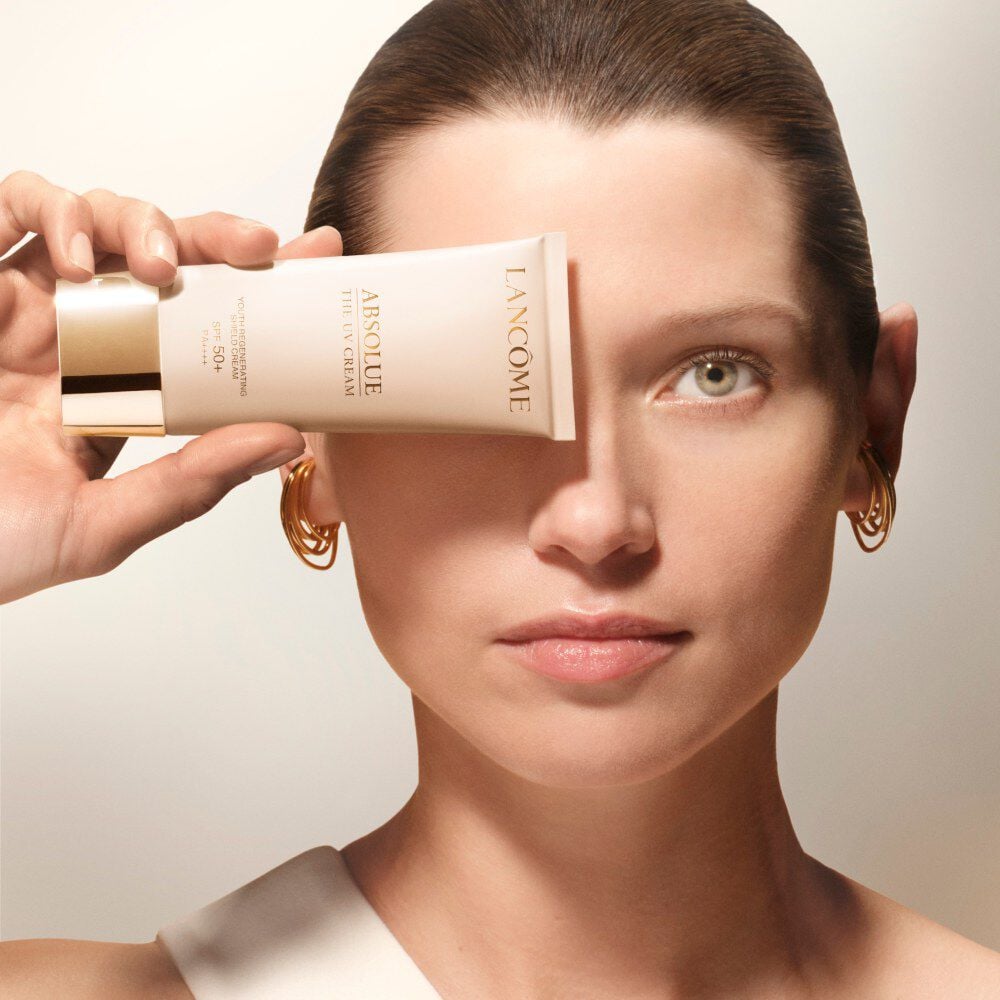 Model holding Absolue the UV Cream close to her face